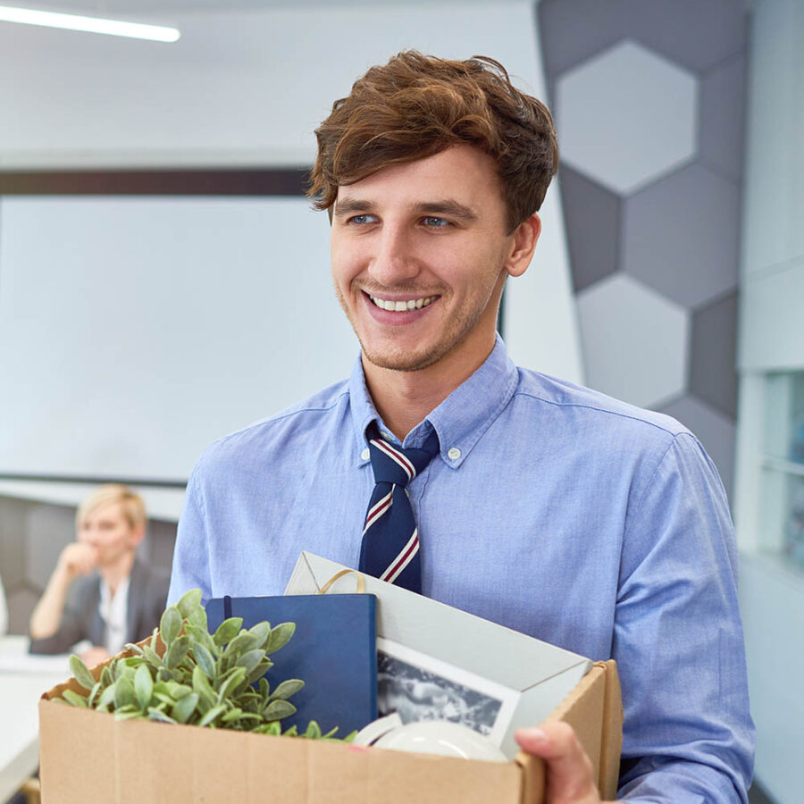 Portrait of smiling young man holding box of personal belongings being hired to work in business company, copy space