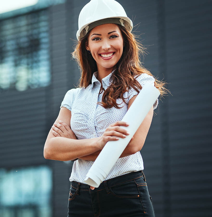 Young successful female engineer with white helmet and blueprints in her hands against urban city background.