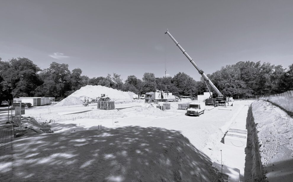 Baustelle Berlin_sw Schwarz-Weißbild von einer Baustelle, mit einem Kran und einem Auto. Die Fläche ist noch ohne Beton, mit Schotter aufgefüllt.
